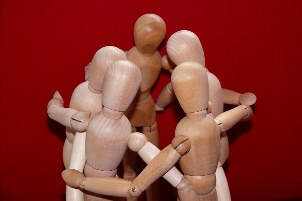 Models of little stick men all huddled in a circle with their heads together