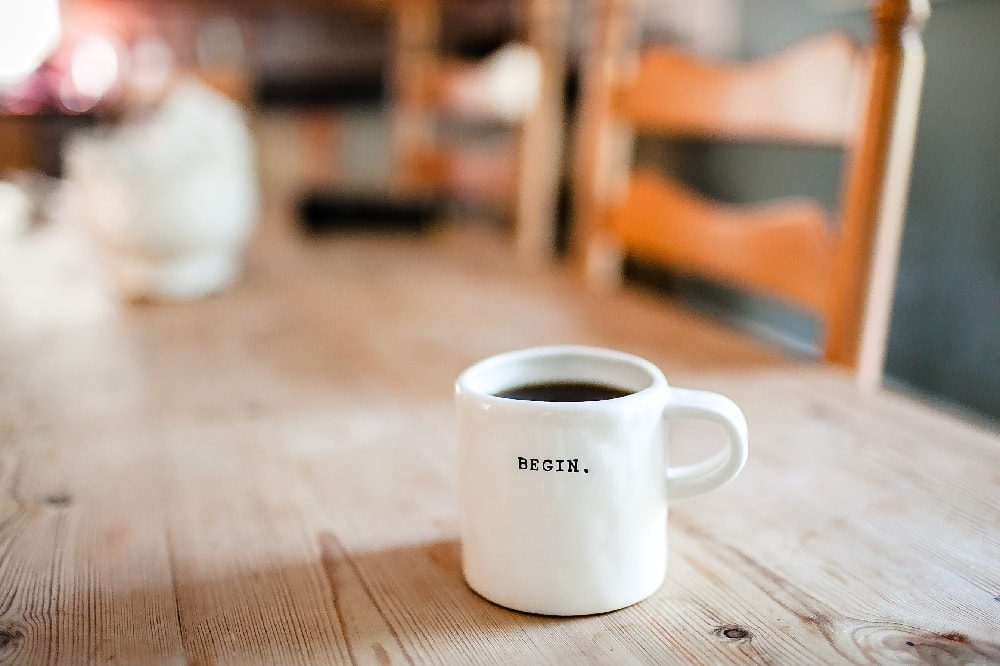 mug on a wooden table that has the word, 'begin' written on it