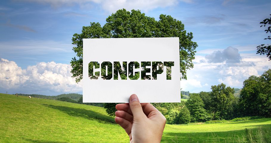 Image of a countryside backdrop with someone holding a piece of paper with the word 'concept' cut out.