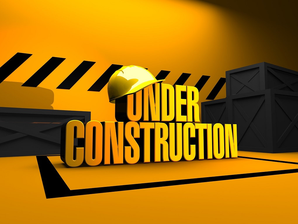 yellow and black image with the words under construction in the middle and a yellow construction hat hanging the on the word under.