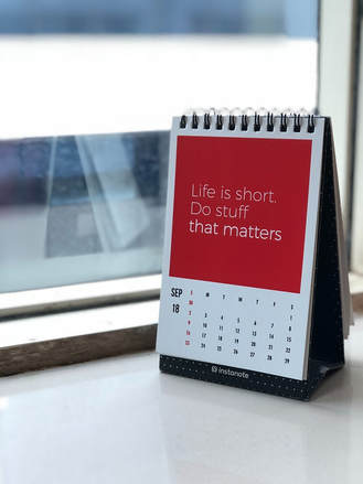 An upright calendar sits on a window sill and above the dates it reads life is short, do stuff that matters.