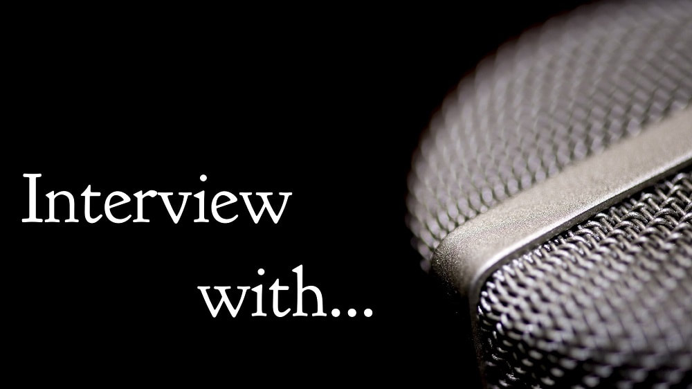 Black background with a close up of the tip of a microphone and the words, interview with, on the left in white