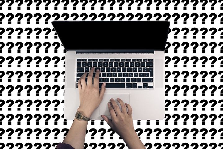 White background with black question marks on top. Laptop in the middle open with hands typing.