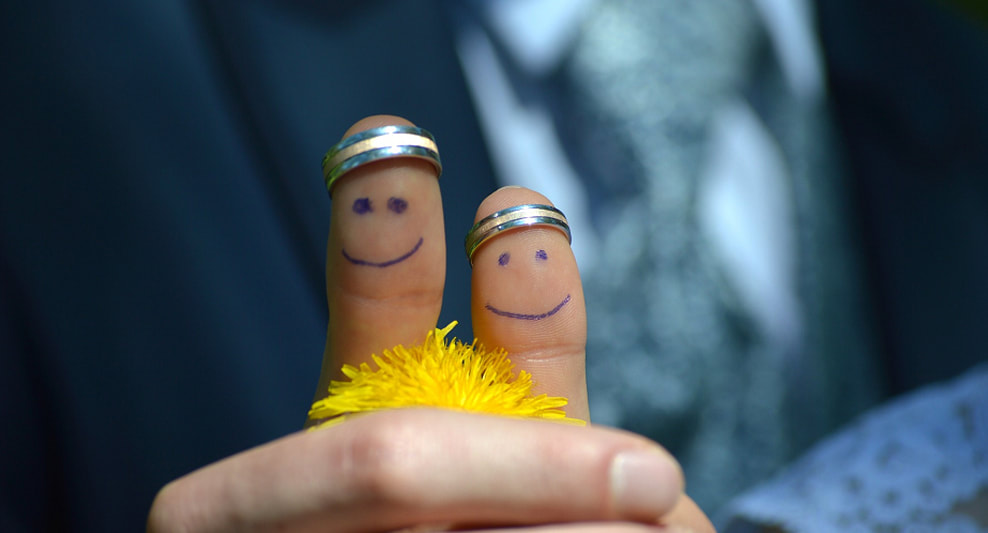 image of 2 thumbs. one of the bride the other of the bridegroom, side by side with smiley faces penned on and wedding bands on the tops of the thumbs.